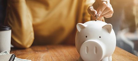 Saving money in a white piggy bank