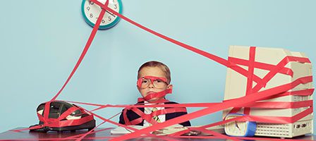Child tangled in red tape at desk