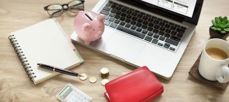 Coffee and wallet beside laptop