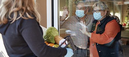 Seniors wave from behind window barrier