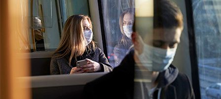 People with masks looking out train window