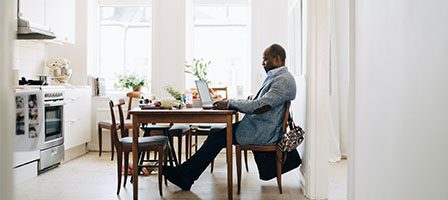 Man working on laptop at kitchen table