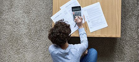 Person using calculator with documents on table