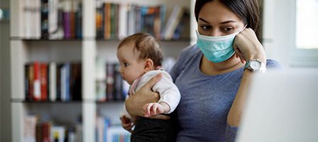 Mother wearing mask holds infant