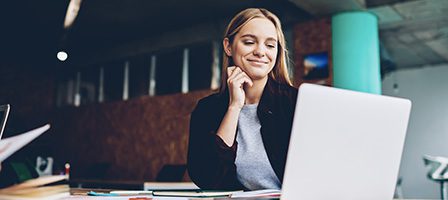 Woman smiling at laptop in office
