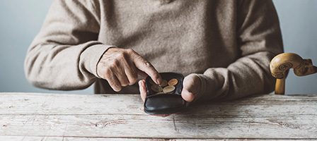 Senior counting coins at table