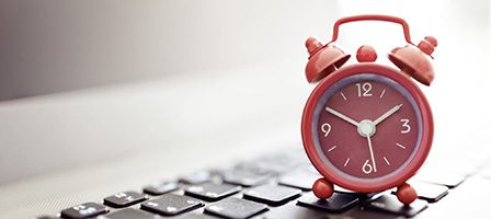 Red alarm clock on computer keyboard