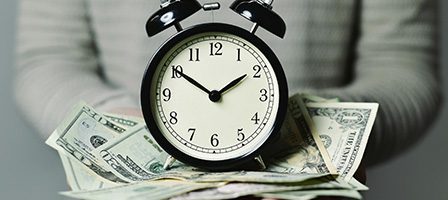 Alarm clock on a pile of money