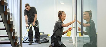 Workers cleaning glass and vacuuming floor