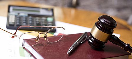 Gavel on desk with glasses and calculator