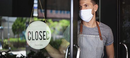 Business closed, worker in apron and mask