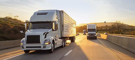 Semi-trucks on open road with sunset