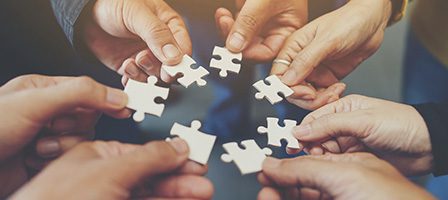 Hands holding jigsaw puzzle pieces together