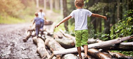 Boys playing on logs in nature