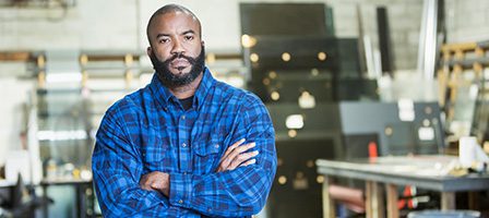 Man in blue plaid shirt, arms crossed
