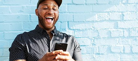 Person smiling at phone outdoors