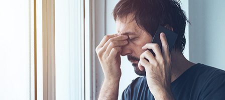 Frustrated man on phone by window