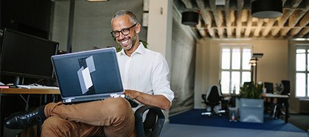 Man smiling while using laptop in office