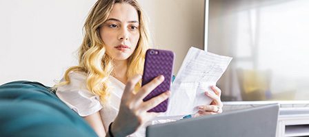 Woman on couch with phone and papers