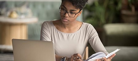 Woman studying with laptop and book