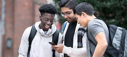 Students laughing while looking at phone