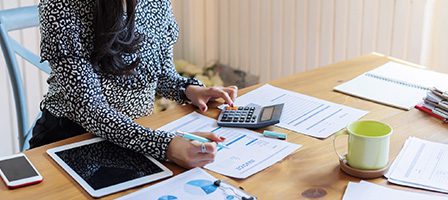 Woman analyzing charts at wooden desk.