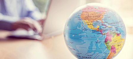 World map globe beside computer