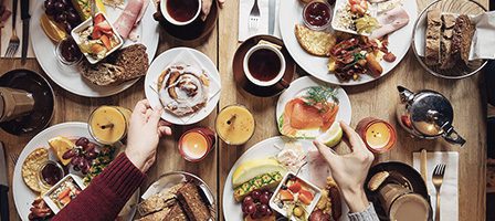 Hands reaching for breakfast food