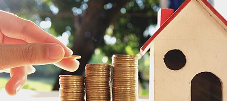 Coins stacked beside small house model