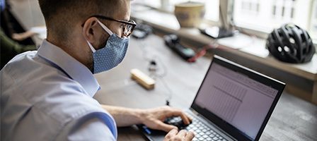 Man working on laptop with mask