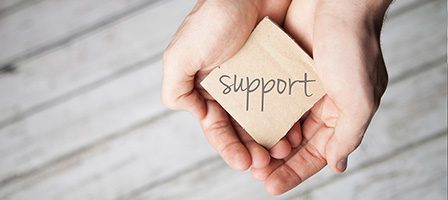 Hands holding a card with "support