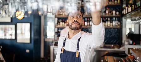Man organizing glassware at counter