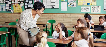 Teacher interacting with attentive students in classroom.