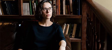 Thoughtful woman relaxing by bookshelves