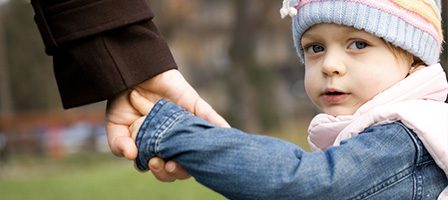 Child holding adult's hand outdoors