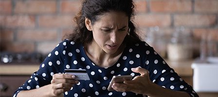 Woman checking phone with credit card