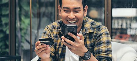 Happy man using mobile device and card
