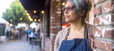 Woman in apron stands by brick wall
