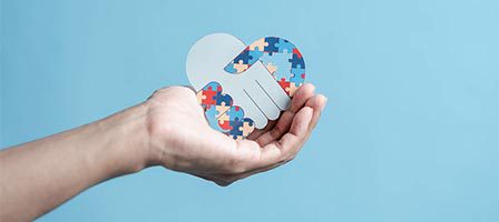 Hand holding puzzle piece heart