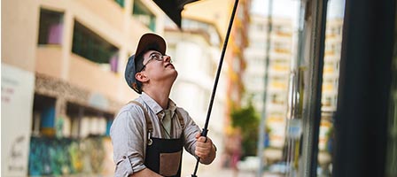 Person cleaning windows with a squeegee pole.