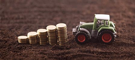 Small green tractor near piles of coins
