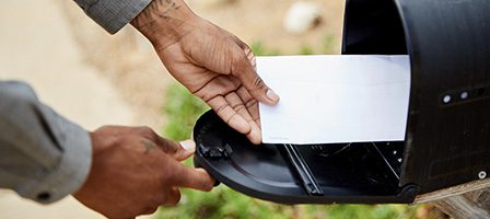 Hand placing envelope in mailbox