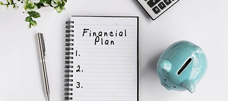 Notebook with financial plan and piggy bank