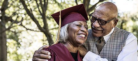 Elderly woman in graduation attire smiling