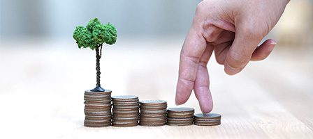 Stacked coins and tiny tree with fingers