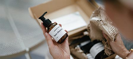 Person holding skincare bottle near packaging
