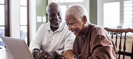 Older couple smiling at laptop