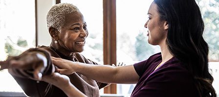 Smiling therapist guiding patient's arm movements