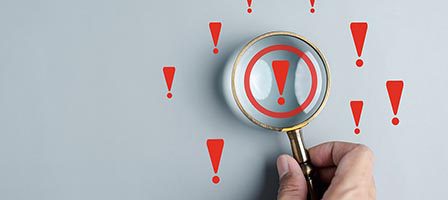 Magnifying glass over red exclamation marks