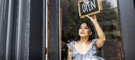Woman hanging open sign in doorway
